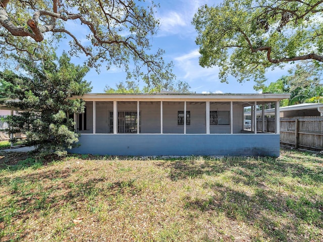 rear view of property featuring a sunroom and fence