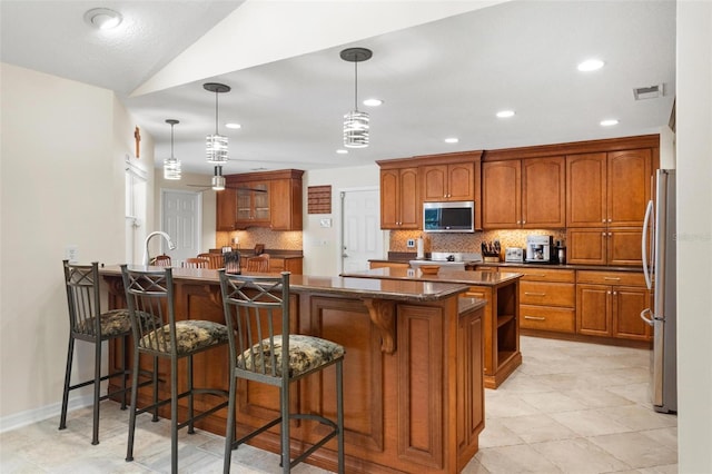 6407 E 112th Ave, Temple Terrace, FL 33617 - kitchen featuring stainless steel appliances, brown cabinets, a kitchen breakfast bar, decorative backsplash, and a peninsula