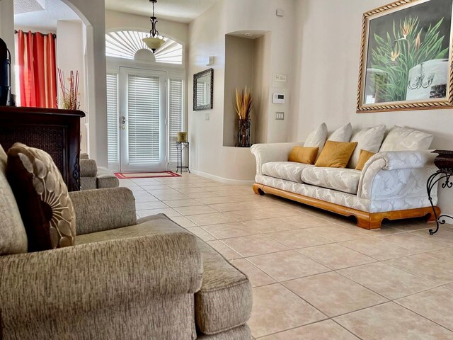 living area featuring baseboards, arched walkways, and tile patterned floors
