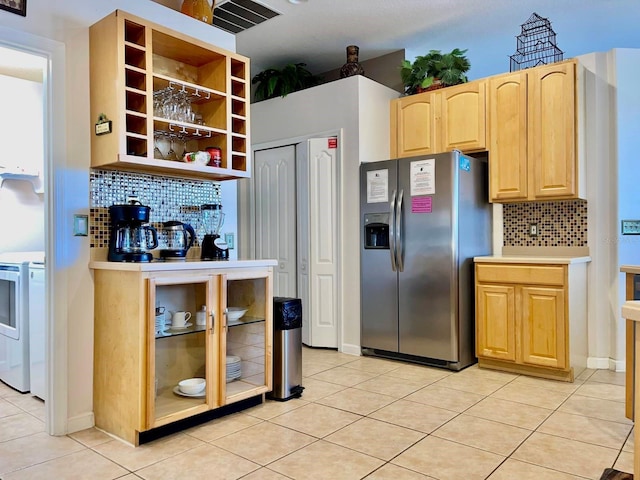 kitchen featuring backsplash, light brown cabinetry, stove, stainless steel fridge with ice dispenser, and light tile patterned flooring