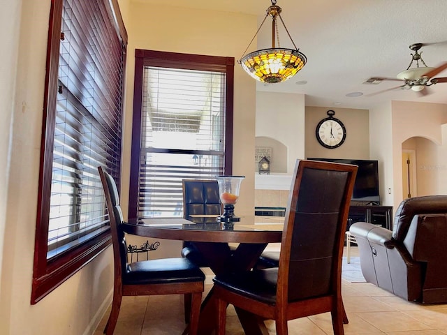 dining space featuring arched walkways, baseboards, visible vents, and light tile patterned flooring