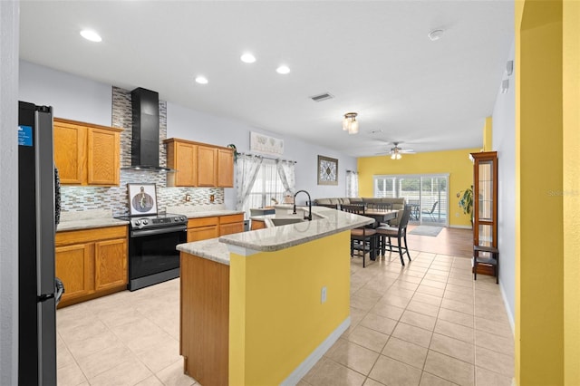 kitchen with a sink, range with electric cooktop, wall chimney exhaust hood, freestanding refrigerator, and a ceiling fan