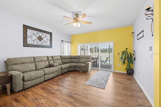 living area featuring a ceiling fan, baseboards, and wood finished floors