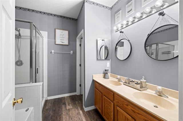 bathroom featuring a sink, double vanity, a shower stall, and wood finished floors