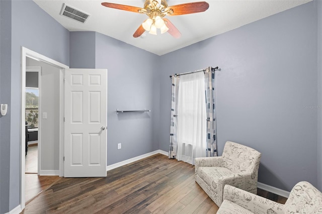 living area with baseboards, ceiling fan, visible vents, and wood finished floors