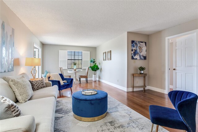 14820 Rue De Bayonne Unit 208, Clearwater, FL 33762 - living room featuring a textured ceiling, baseboards, and wood finished floors