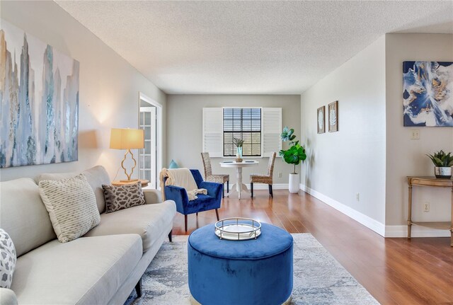14820 Rue De Bayonne Unit 208, Clearwater, FL 33762 - living room featuring baseboards, a textured ceiling, and wood finished floors