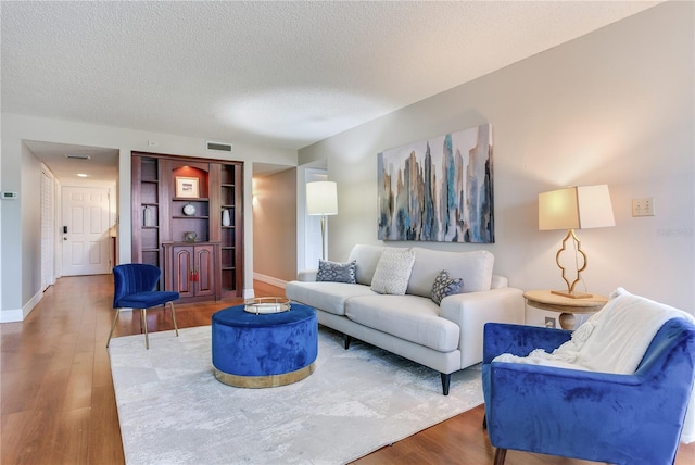 14820 Rue De Bayonne Unit 208, Clearwater, FL 33762 - living room featuring baseboards, a textured ceiling, visible vents, and wood finished floors