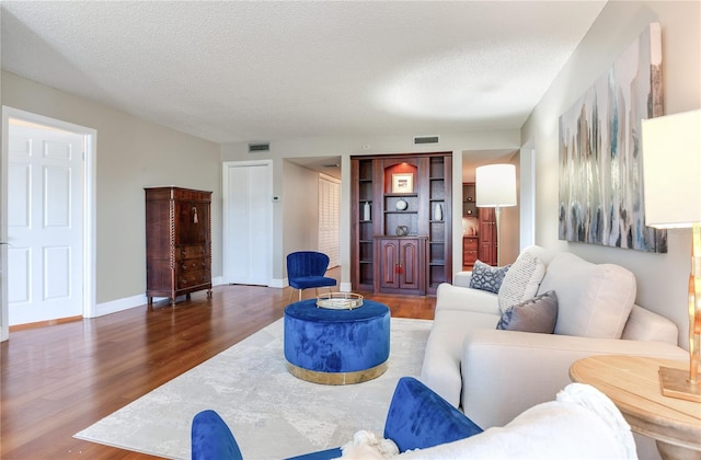 14820 Rue De Bayonne Unit 208, Clearwater, FL 33762 - living area with baseboards, a textured ceiling, visible vents, and wood finished floors