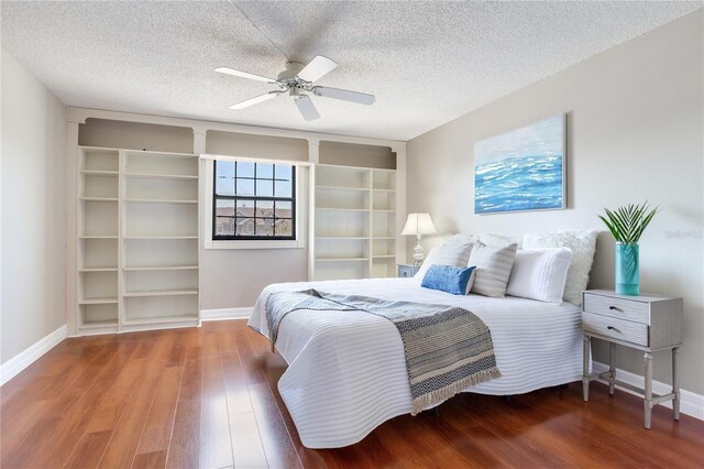 14820 Rue De Bayonne Unit 208, Clearwater, FL 33762 - bedroom with a textured ceiling, baseboards, a ceiling fan, and wood finished floors