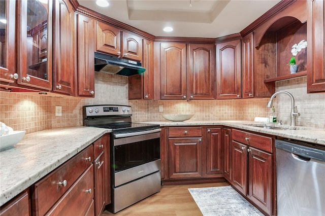 14820 Rue De Bayonne Unit 208, Clearwater, FL 33762 - kitchen with light stone counters, a sink, a raised ceiling, stainless steel appliances, and under cabinet range hood