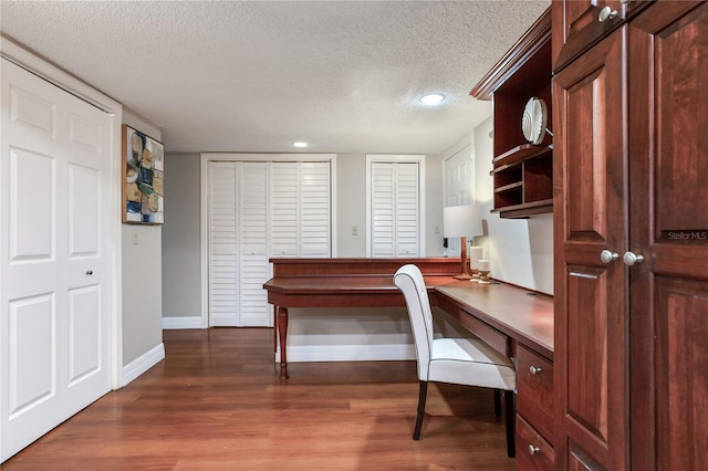 14820 Rue De Bayonne Unit 208, Clearwater, FL 33762 - office area with baseboards, a textured ceiling, built in desk, and wood finished floors