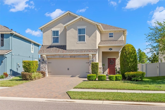 view of front of home featuring fence, an attached garage, stone siding, stucco siding, and decorative driveway