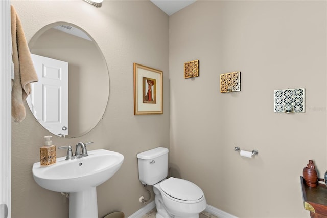 bathroom featuring toilet, baseboards, visible vents, and a sink