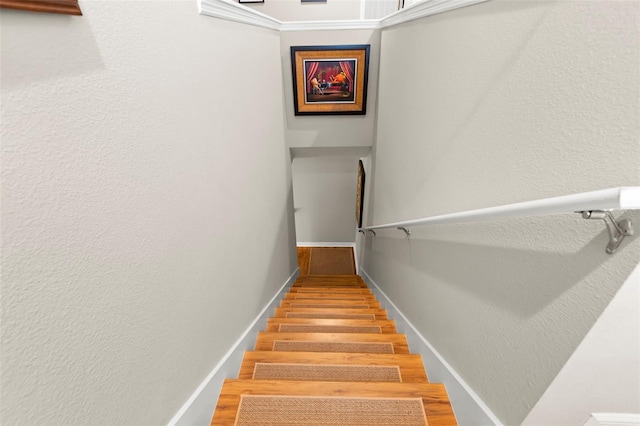 stairway featuring baseboards and a textured wall