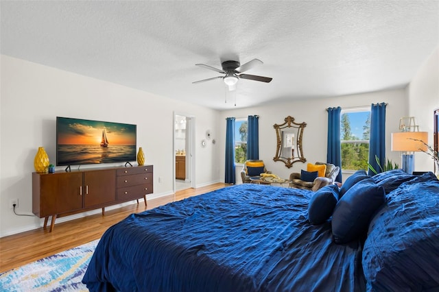 bedroom with a ceiling fan, a textured ceiling, wood finished floors, and ensuite bathroom