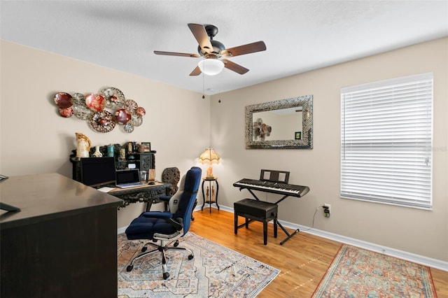 home office featuring light wood-style floors, a ceiling fan, and baseboards
