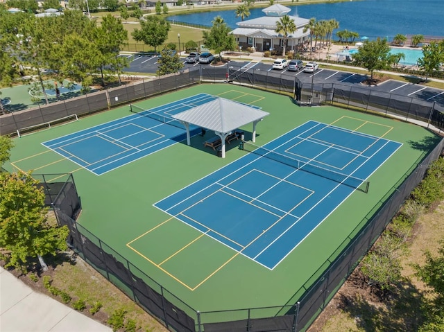 view of sport court with a water view and fence