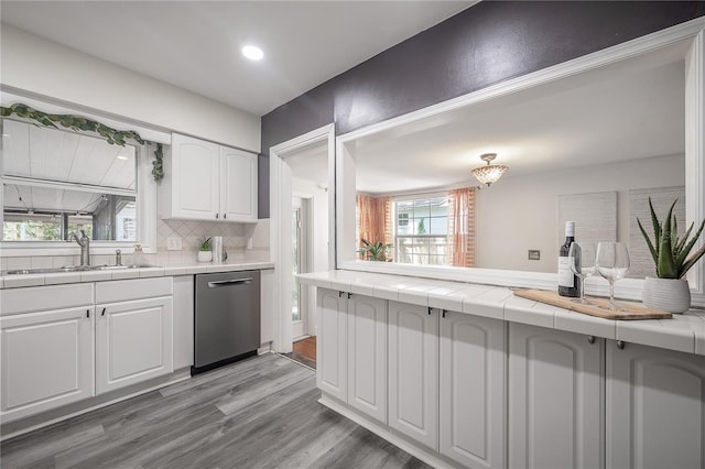 1211 E Park Cir, Tampa, FL 33604 - kitchen with dishwasher, a sink, white cabinets, light wood-style flooring, and tile counters