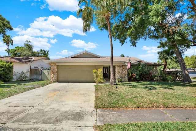 single story home with concrete driveway, a front yard, an attached garage, and stone siding