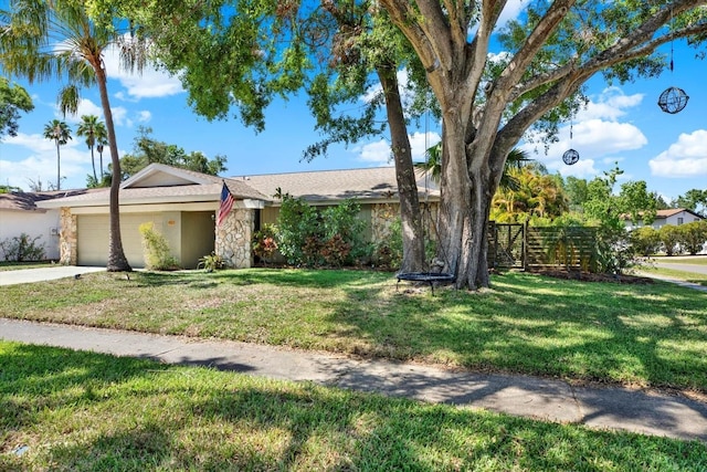 single story home with concrete driveway, an attached garage, stone siding, and a front lawn