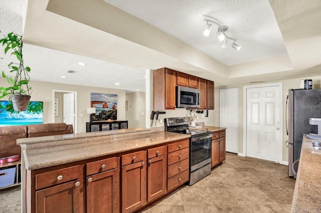 kitchen with stainless steel appliances, a textured ceiling, open floor plan, and a peninsula