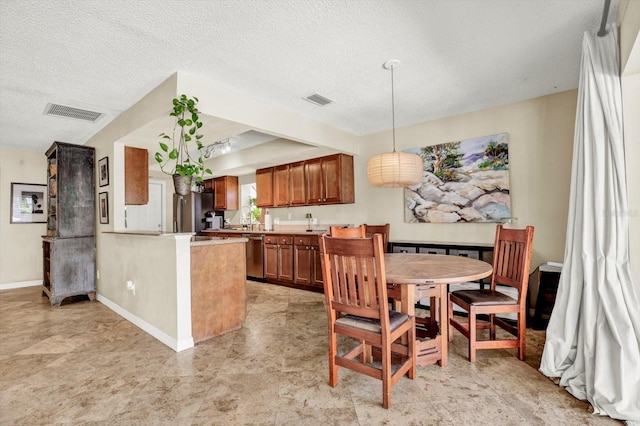 kitchen featuring brown cabinetry, visible vents, light countertops, a peninsula, and stainless steel appliances