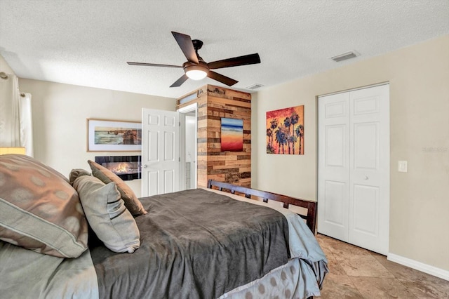 bedroom with baseboards, a ceiling fan, a textured ceiling, and visible vents