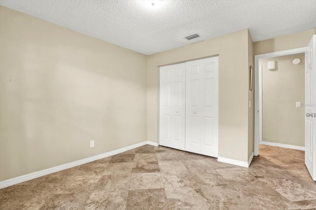 unfurnished bedroom with visible vents, a textured ceiling, baseboards, and a closet