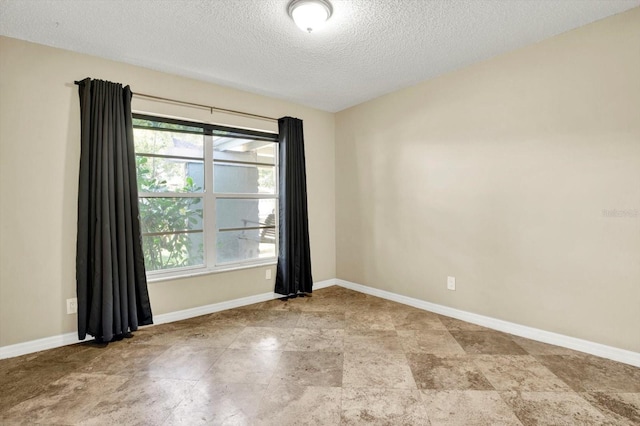 empty room with a healthy amount of sunlight, baseboards, and a textured ceiling