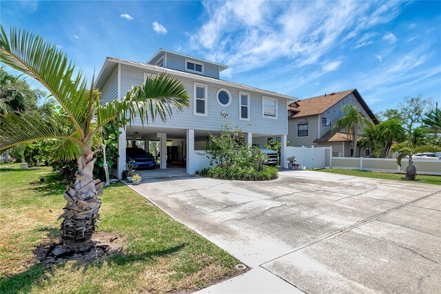 13974 75th Ave, Seminole, FL 33776 - coastal inspired home featuring a carport, driveway, and fence