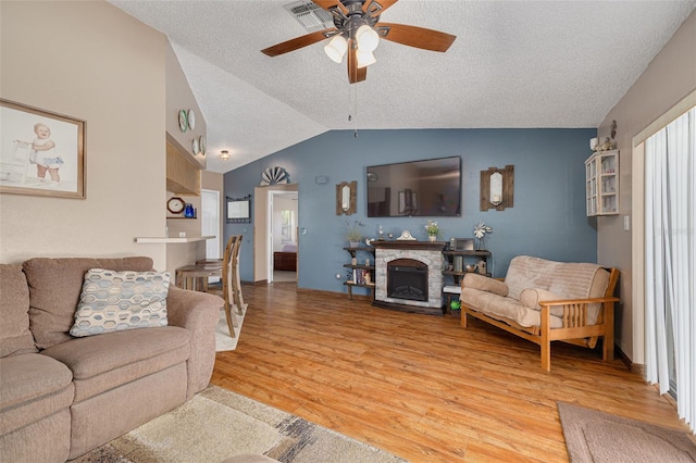 2153 Catalina Dr N, Clearwater, FL 33763 - living room with light wood-style flooring, ceiling fan, a textured ceiling, lofted ceiling, and a stone fireplace
