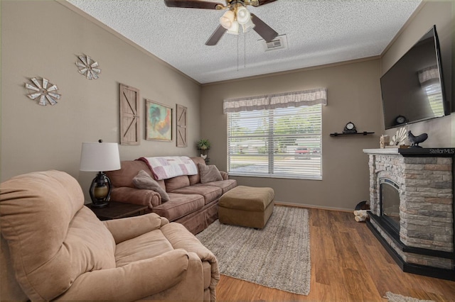 2153 Catalina Dr N, Clearwater, FL 33763 - living area featuring a textured ceiling, ceiling fan, wood finished floors, a fireplace, and baseboards
