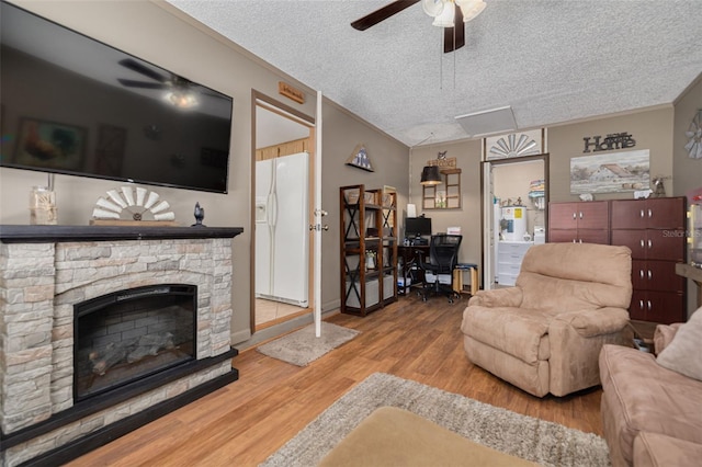 2153 Catalina Dr N, Clearwater, FL 33763 - living room featuring ceiling fan, a textured ceiling, a desk, wood finished floors, and a stone fireplace