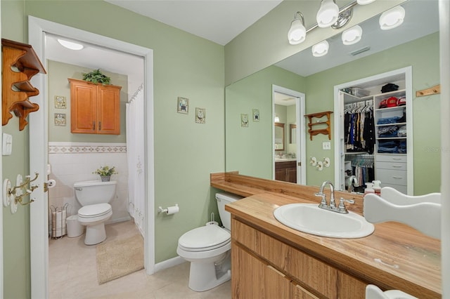2153 Catalina Dr N, Clearwater, FL 33763 - bathroom with toilet, tile patterned floors, vanity, a walk in closet, and tile walls