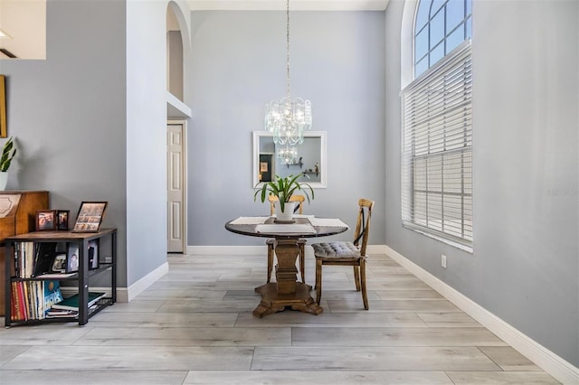 18013 Palm Breeze Dr, Tampa, FL 33647 - dining space featuring wood finished floors, baseboards, a high ceiling, arched walkways, and a notable chandelier