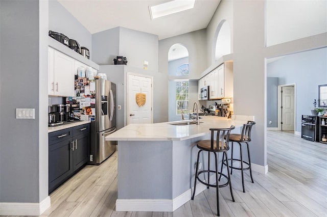 18013 Palm Breeze Dr, Tampa, FL 33647 - kitchen featuring a kitchen breakfast bar, appliances with stainless steel finishes, a peninsula, light wood-style floors, and a high ceiling