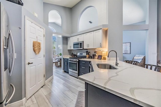 18013 Palm Breeze Dr, Tampa, FL 33647 - kitchen with light stone countertops, a sink, baseboards, stainless steel appliances, and white cabinetry