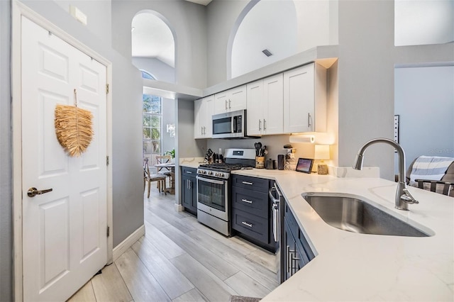 18013 Palm Breeze Dr, Tampa, FL 33647 - kitchen with appliances with stainless steel finishes, light stone countertops, a sink, white cabinets, and light wood finished floors