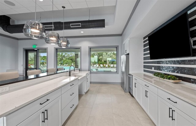 interior space with visible vents, a tray ceiling, tasteful backsplash, light tile patterned floors, and decorative light fixtures