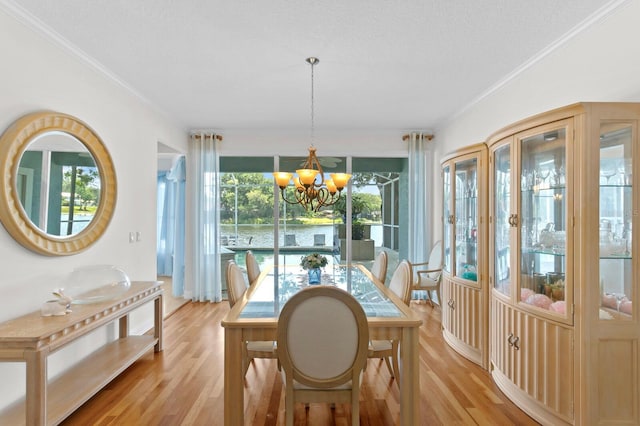 dining room with light wood-style floors, crown molding, and a notable chandelier