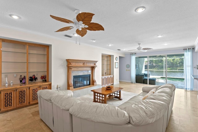 living area with a ceiling fan, a textured ceiling, visible vents, crown molding, and a premium fireplace