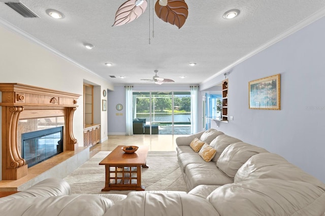 living area featuring crown molding, built in shelves, a ceiling fan, and a textured ceiling