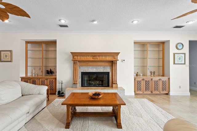 living area with crown molding, a ceiling fan, a textured ceiling, and visible vents