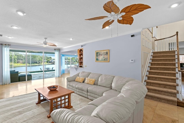 living room with stairs, ceiling fan, light tile patterned floors, and a wealth of natural light
