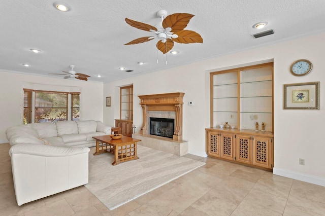 living room featuring crown molding, visible vents, baseboards, a high end fireplace, and a ceiling fan