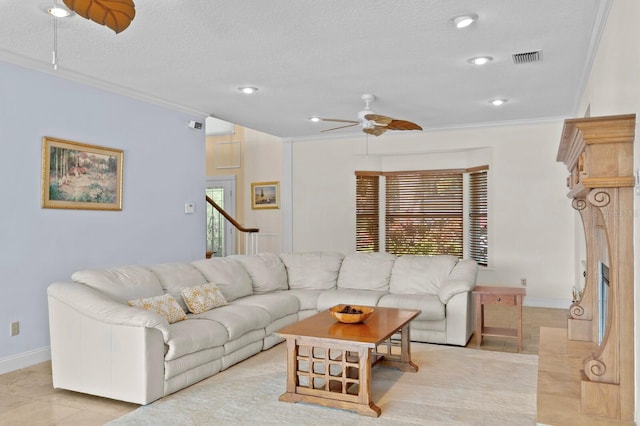 living room with a ceiling fan, visible vents, light tile patterned floors, baseboards, and ornamental molding
