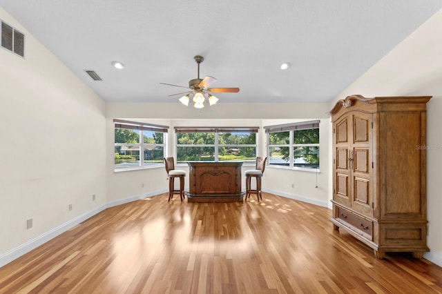 living area featuring a healthy amount of sunlight, baseboards, a ceiling fan, and visible vents