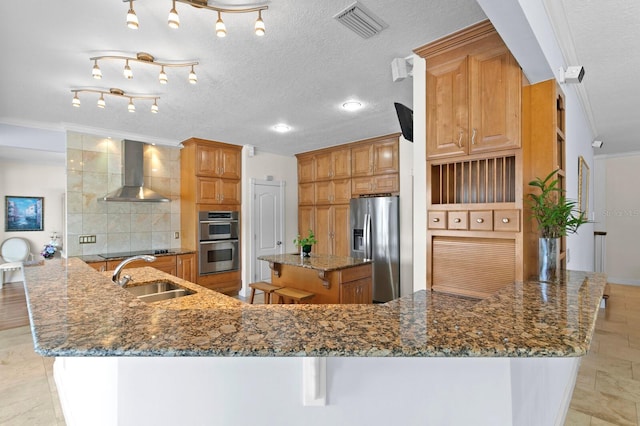 kitchen with crown molding, visible vents, wall chimney range hood, a sink, and appliances with stainless steel finishes