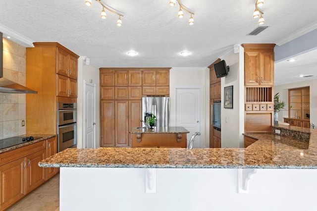 kitchen featuring a center island, a kitchen bar, wall chimney range hood, and stainless steel appliances
